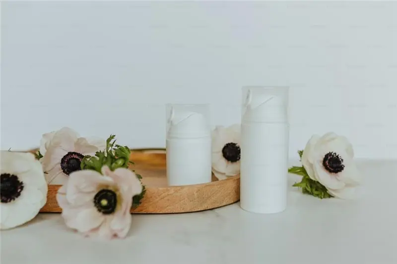 Minimalist white skincare containers displayed with flowers, symbolizing eco-friendly skincare packaging