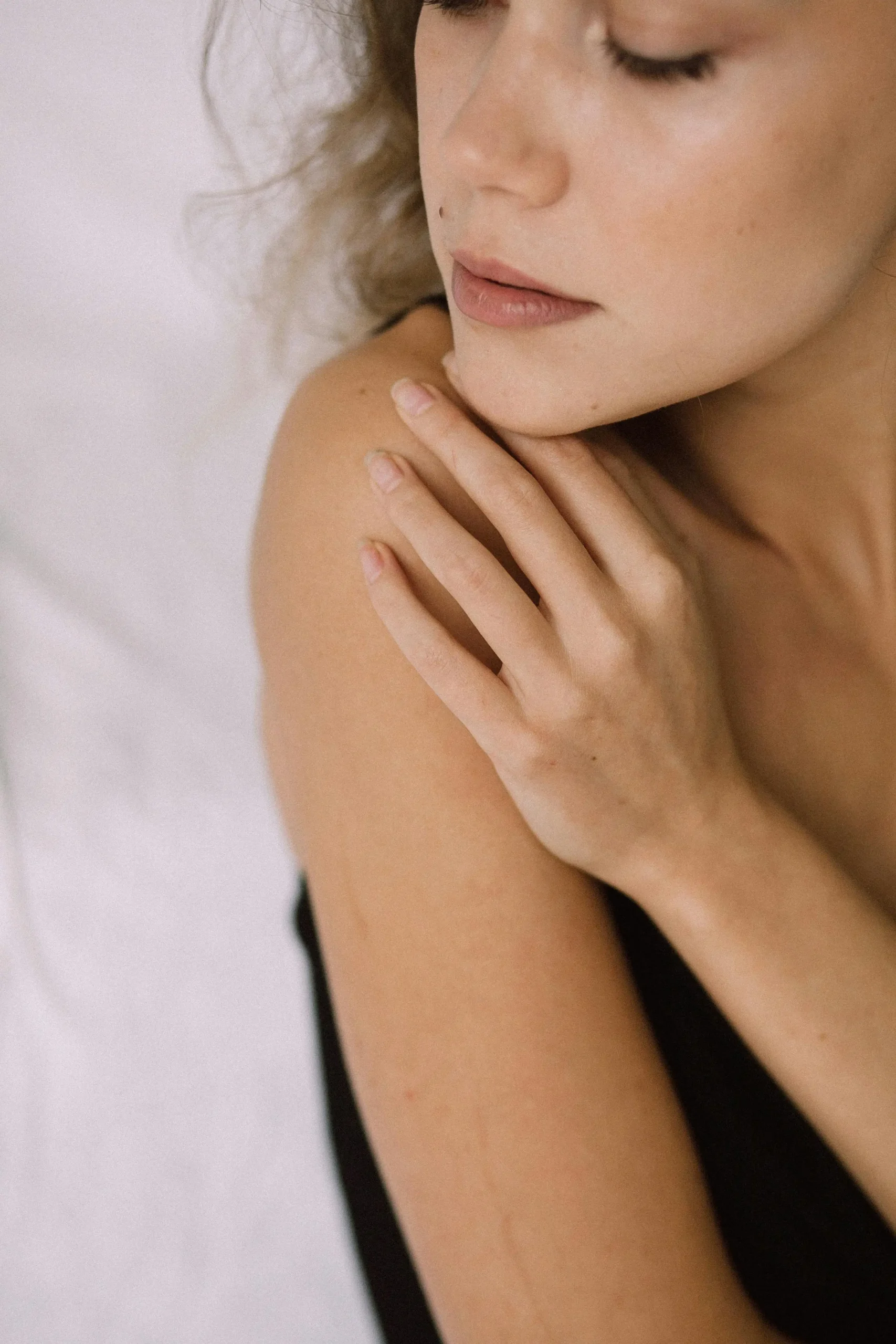 Close-up of a person touching their shoulder, representing gentle skincare for sensitive skin