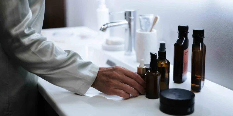 Hand selecting skincare products on a bathroom counter, illustrating seasonal skincare tips for adjusting a routine year-round