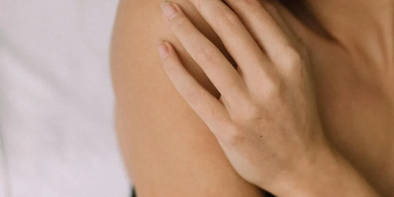 Close-up of a person touching their shoulder, representing gentle skincare for sensitive skin